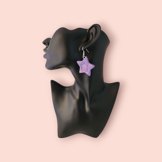 Purple star-shaped earring on a black mannequin ear with a pink background