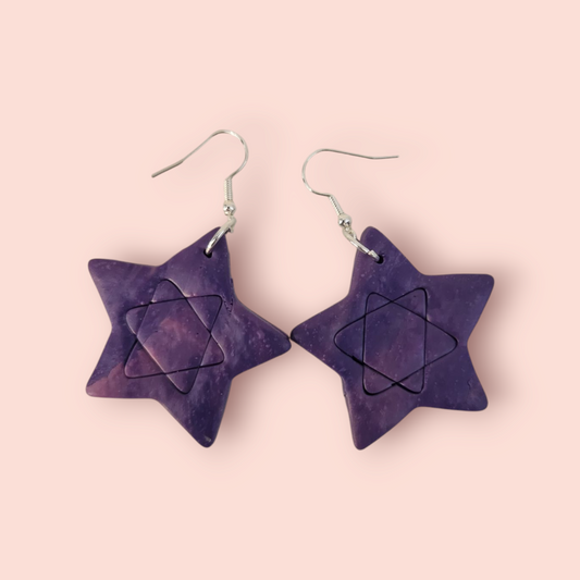 A pair of purple star-shaped earrings with intricate geometric patterns, hanging from fishhook clasps.