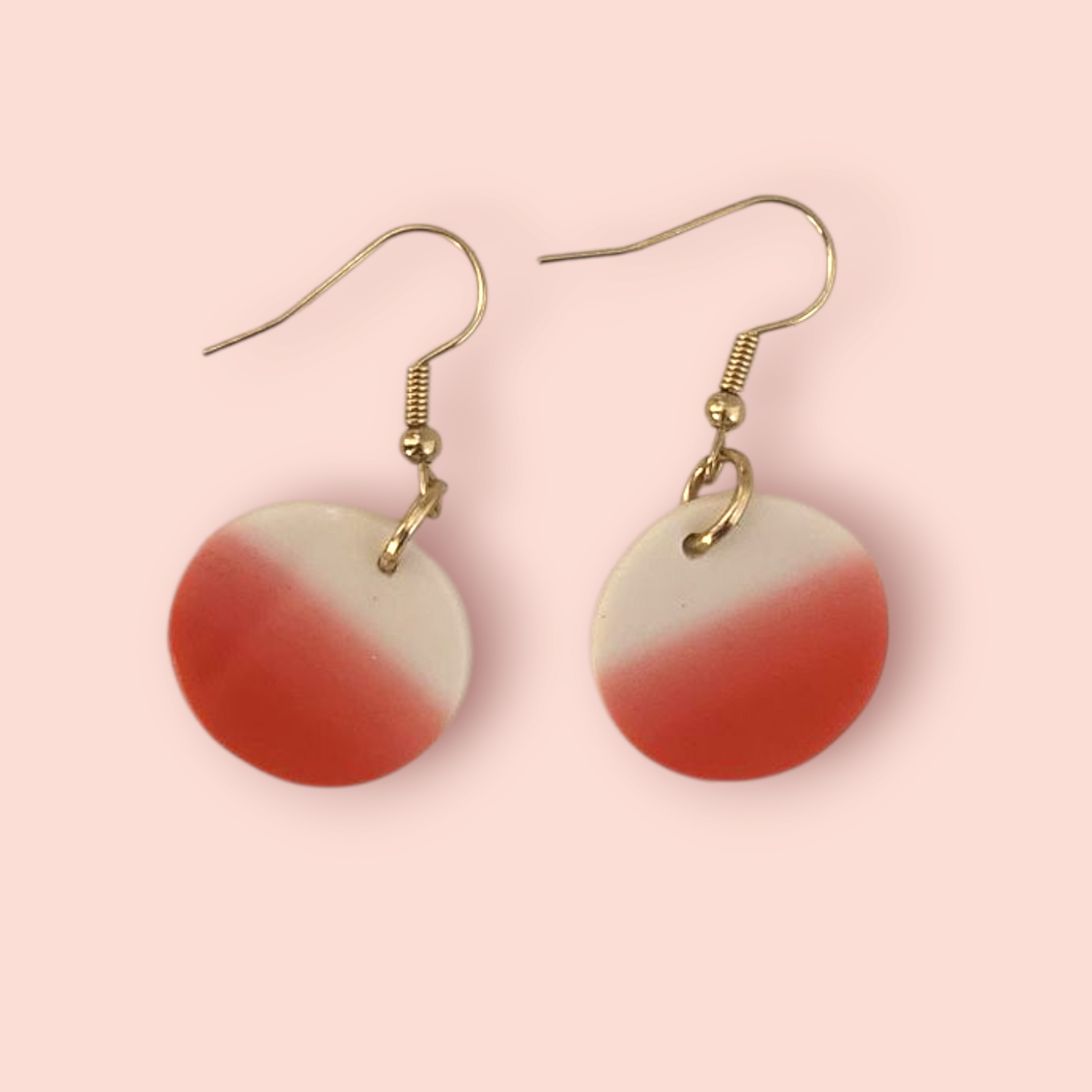 Pair of earrings with red and white gradient on a pink background
