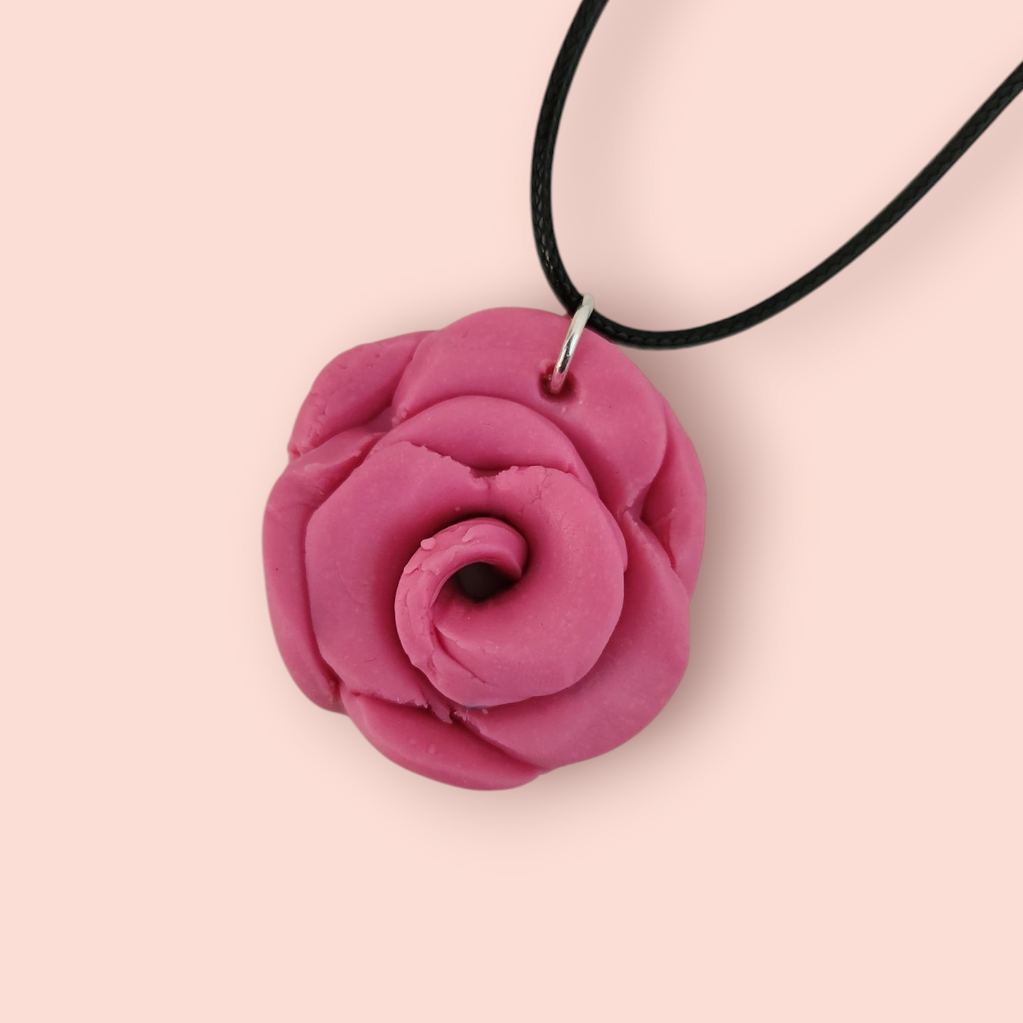 A pink polymer clay pendant shaped like a rose.