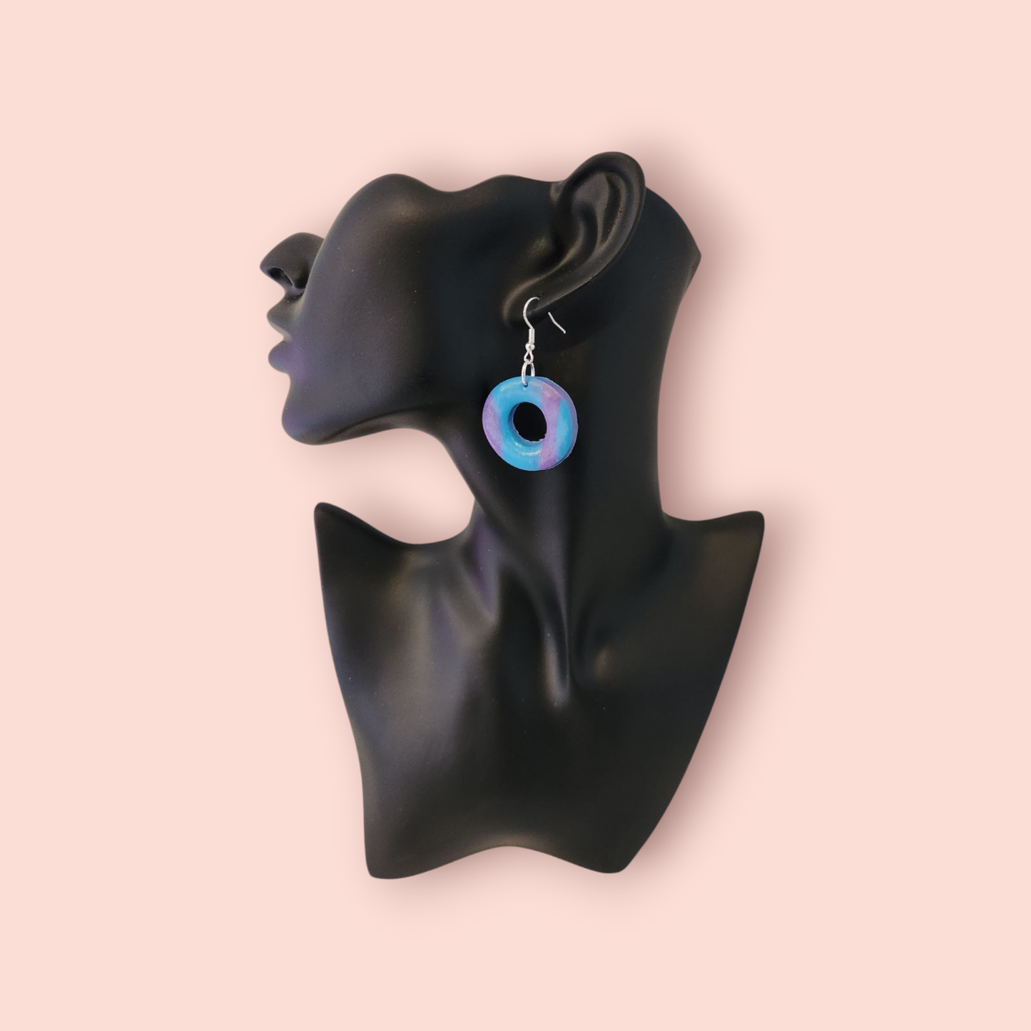 A round earrings with a pattern of blue and purple stripes.